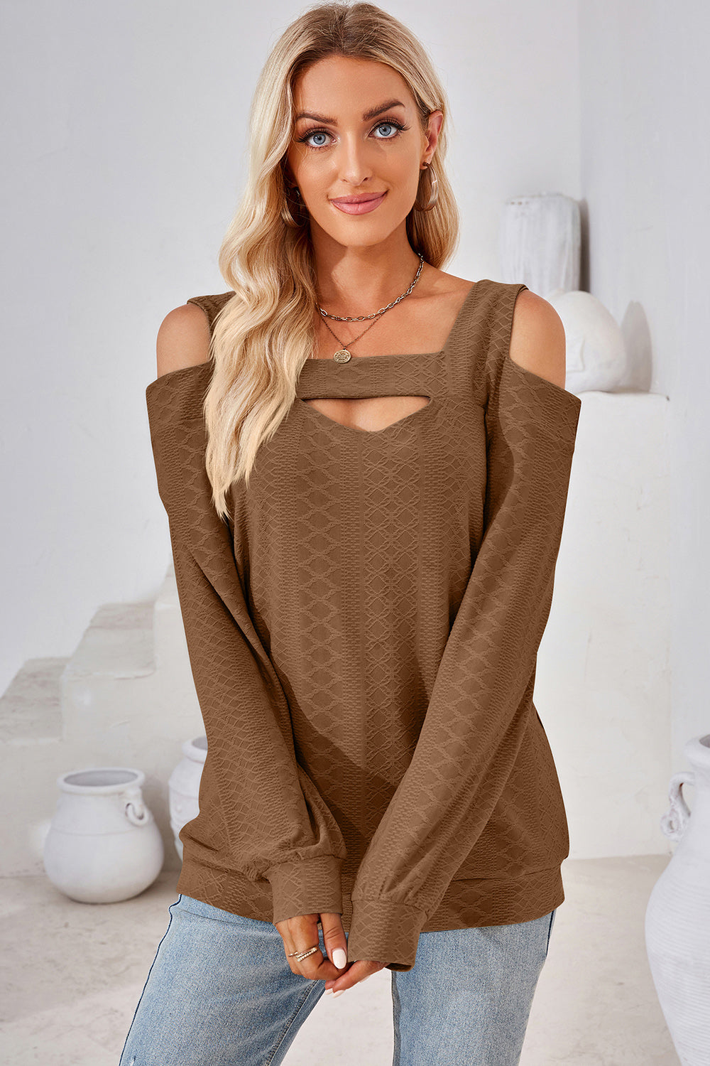 Brown geometric cutout shoulder top with a square neckline and long sleeves.