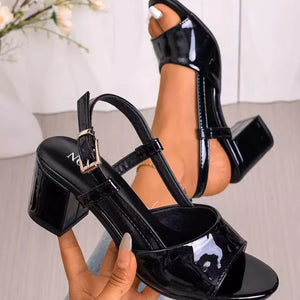 Black patent open-toe block heel sandals with ankle strap and buckle.