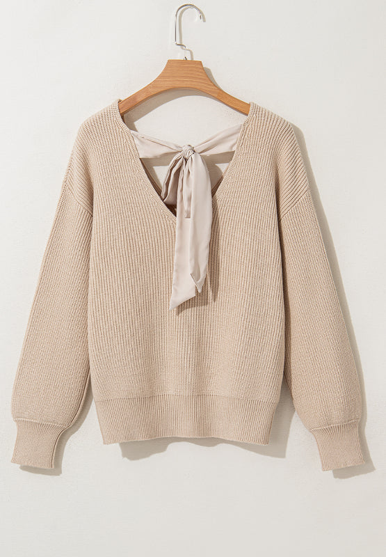 Beige ribbed knit sweater with V-neck and satin bow detail at the back.
