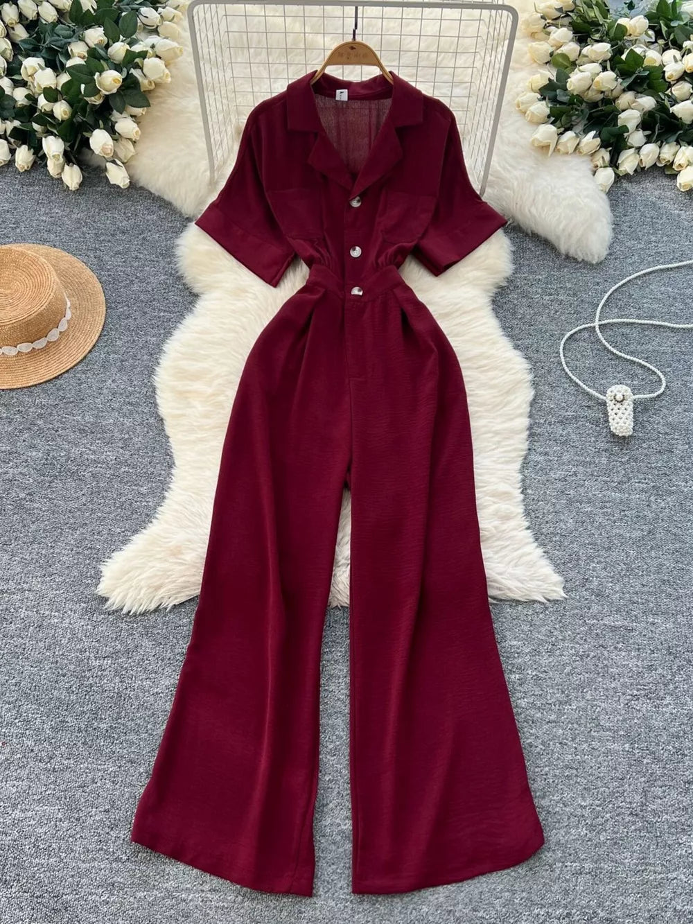 Burgundy belted wide-leg maternity jumpsuit with button front and short sleeves.