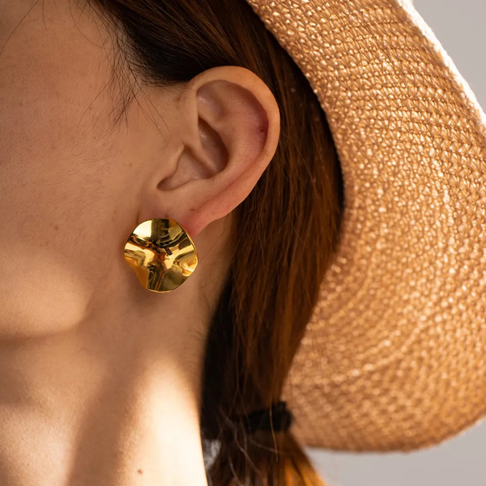 Sculpted gold wave stud earrings with a textured, organic design.