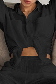 Black textured cotton lounge set with button-up shirt tied at waist and matching pants.
