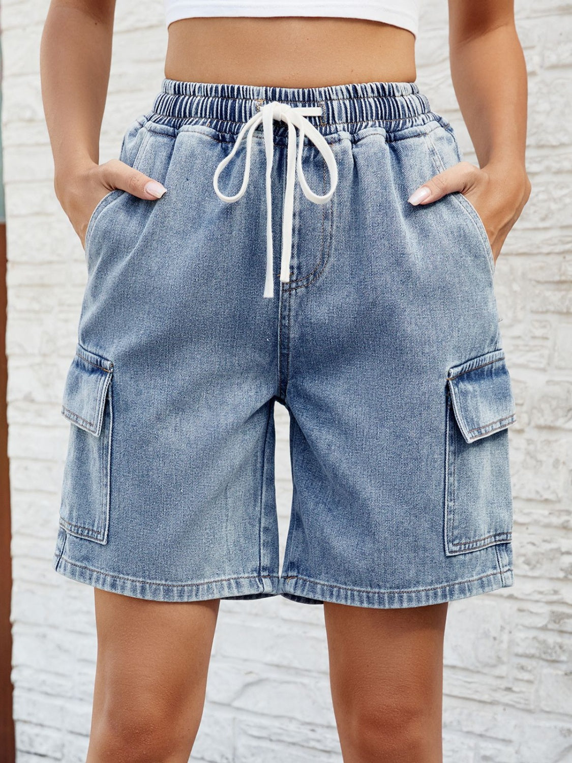 Denim cargo shorts in dusty blue with drawstring waist and side pockets.