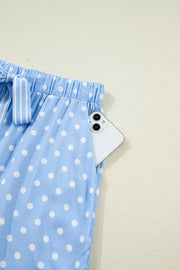 Blue polka dot viscose pajama pants with a white drawstring and a side pocket holding a phone.