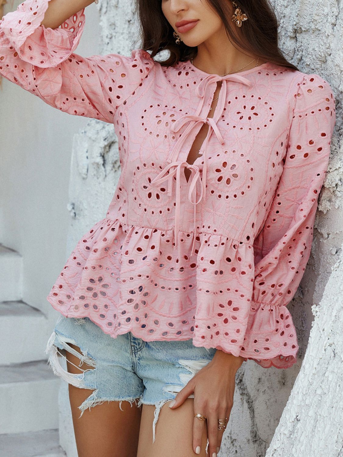 Dusty pink eyelet embroidered peplum blouse with tie neck and ruffled cuffs.