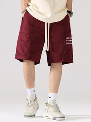Maroon red 100% cotton cargo shorts with adjustable drawstring and side pocket text detail.