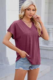 Dolman sleeve slouchy v-neck top in red-violet, styled casually with denim shorts.