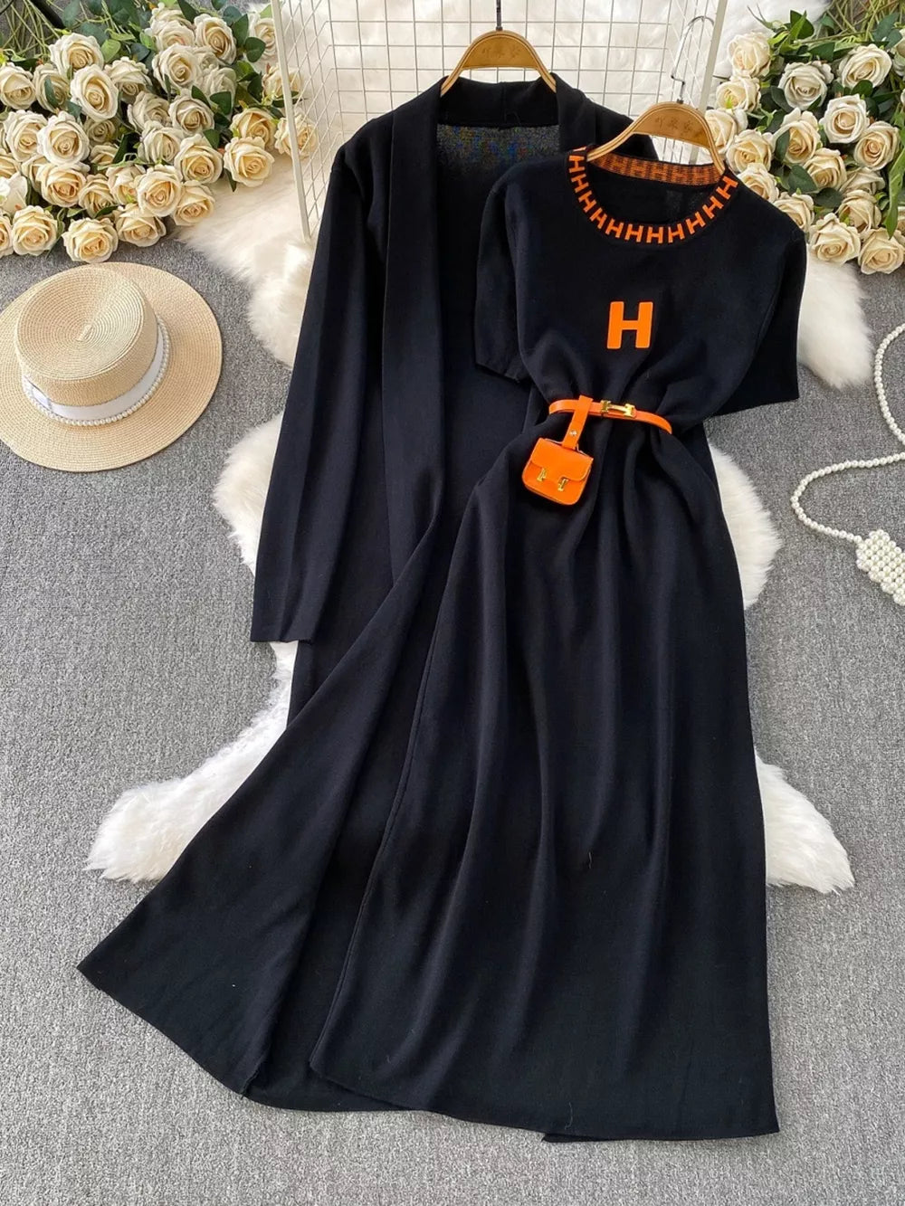Black knitted maxi dress and cardigan set with orange 'H' detail and belt.