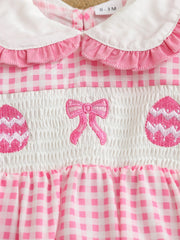 Pink gingham baby one-piece with smocking, embroidered bow, and Easter eggs.
