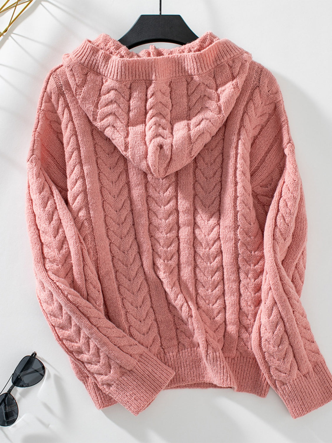 Cable knit hooded sweater in burnt coral with textured stitching and ribbed cuffs.