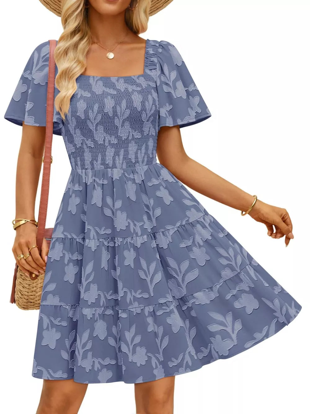 Smocked mini dress in dusty blue with tiered skirt and floral pattern. Square neck, flutter sleeves.
