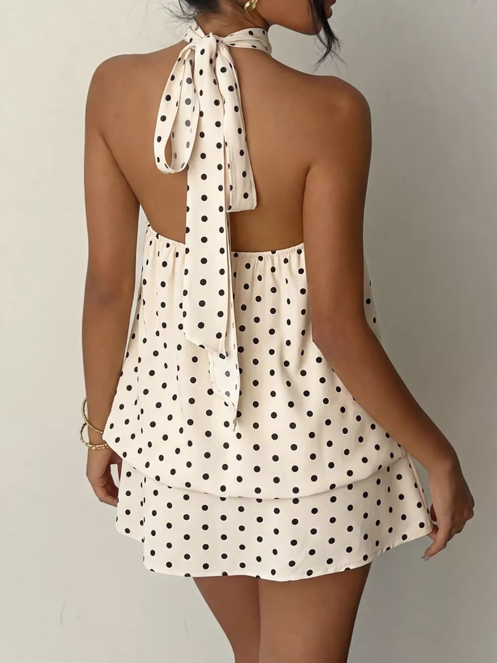 Apricot polka dot halter mini dress with tie back and tiered skirt.