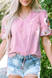 Dusty pink peasant blouse with embroidered puff sleeves and tie neckline.