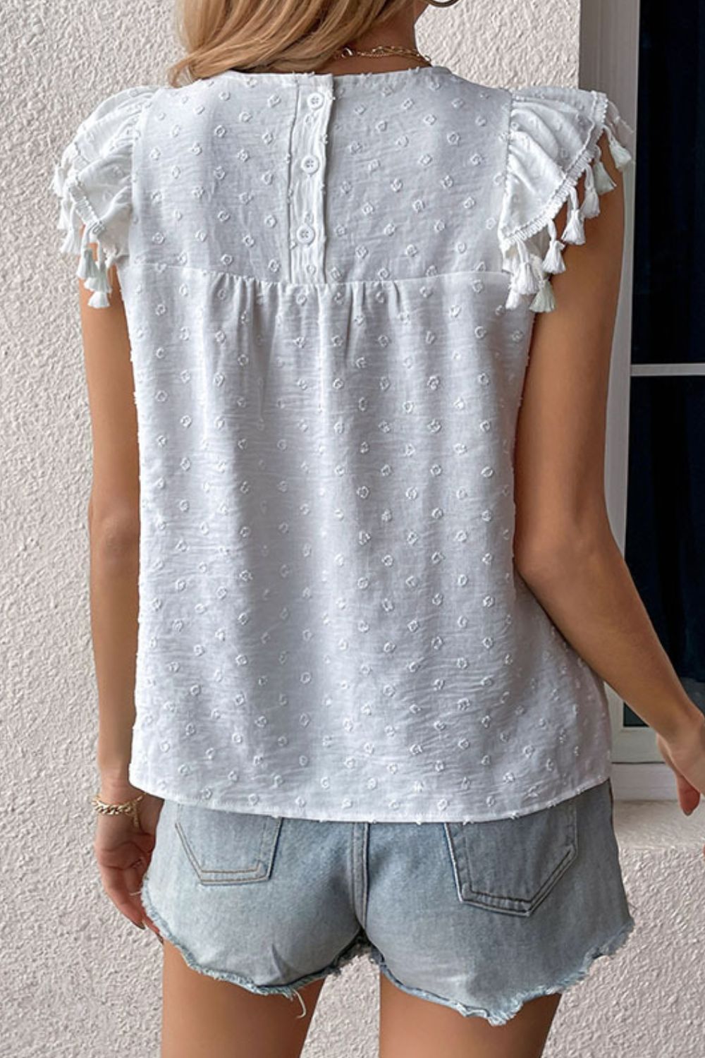 White dotted swiss blouse with cap sleeves and tassel details, button back