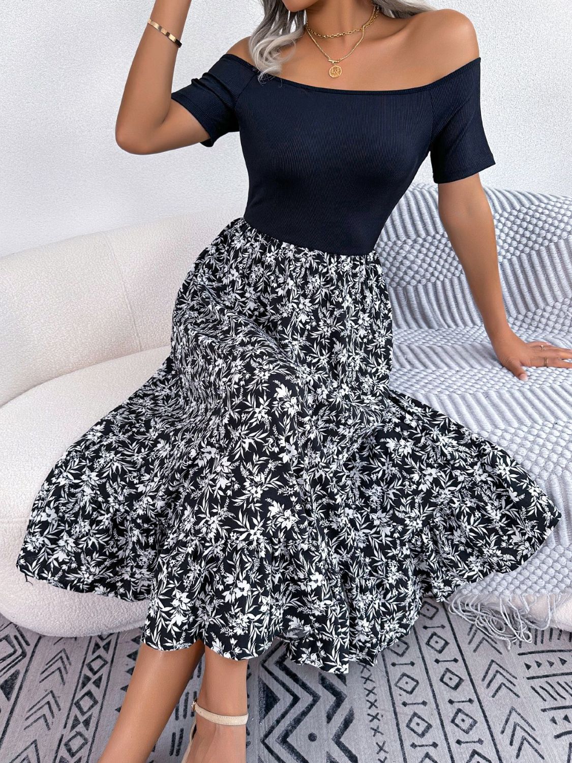 Black off-shoulder midi dress with a floral print skirt and short sleeves.