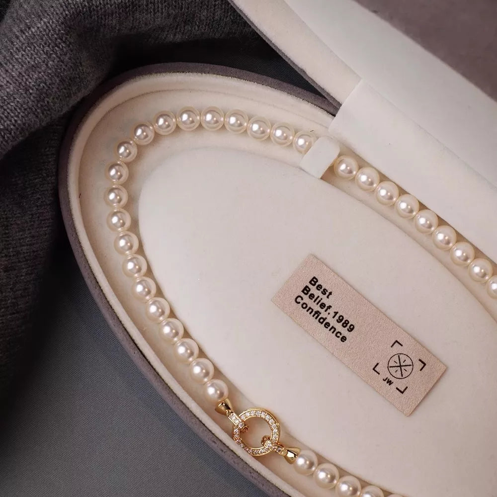 Cream pearl choker necklace with 18k gold clasp and diamond accents.