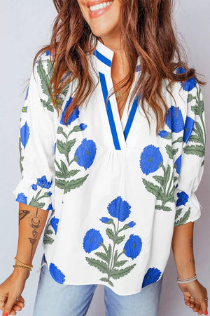 White cotton blouse with blue floral print, notched neckline, and ruffled sleeves.