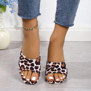 Leopard print block heel mules with open toe and white toenails.