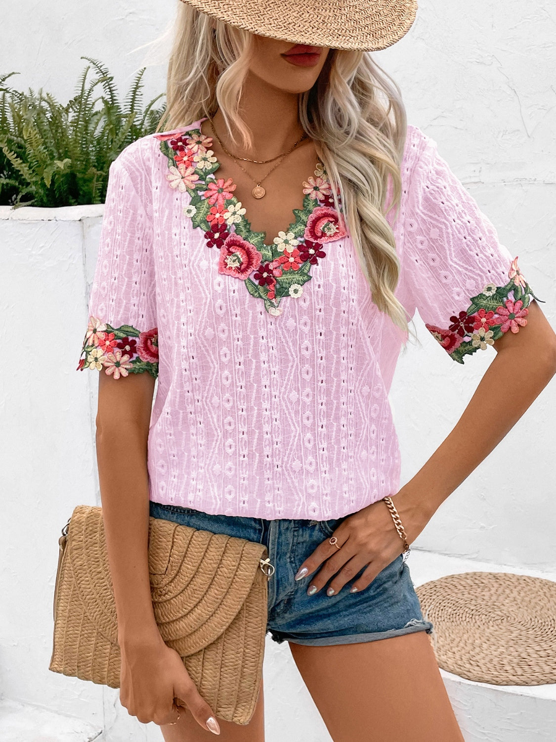 Blush pink embroidered eyelet v-neck peasant blouse with floral trim on neckline and sleeves.