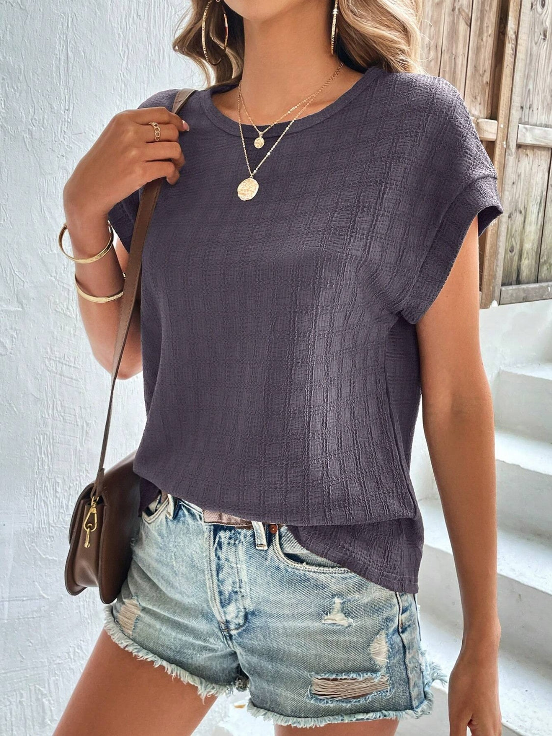 Woven texture cap-sleeve top in dark grey with a crew neck, styled casually with denim shorts.