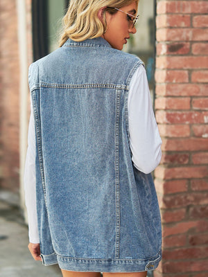 Light wash denim longline vest with collared neckline and utility details, worn over a white long sleeve shirt.