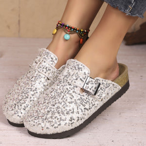 Sparkling sequin slip-on mules in white with decorative buckle detail.