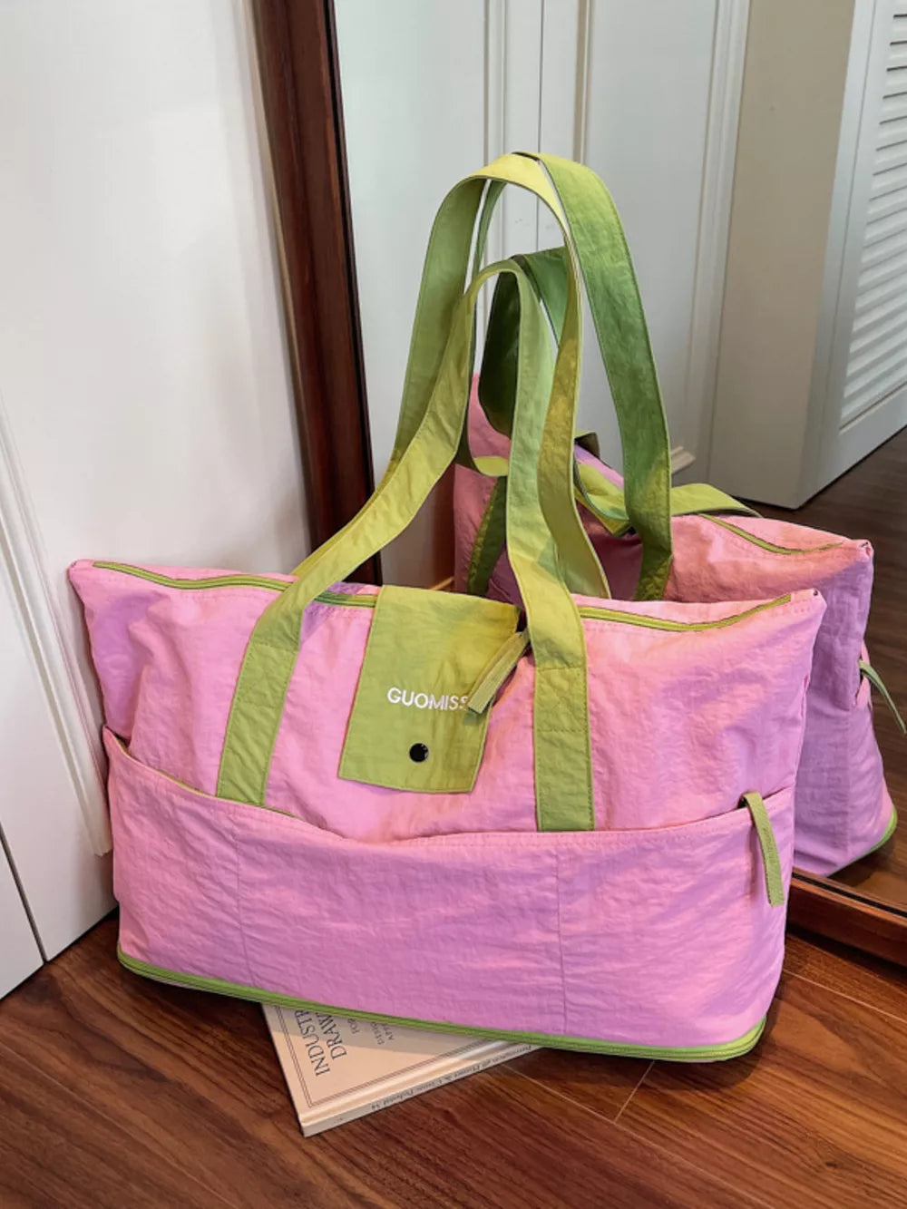 Pink and green two-tone nylon travel bag with front pockets and GUOMISS logo detail.