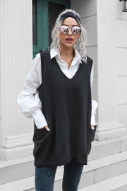 Black oversized knit vest with V-neck and large front pockets, styled over a white shirt.