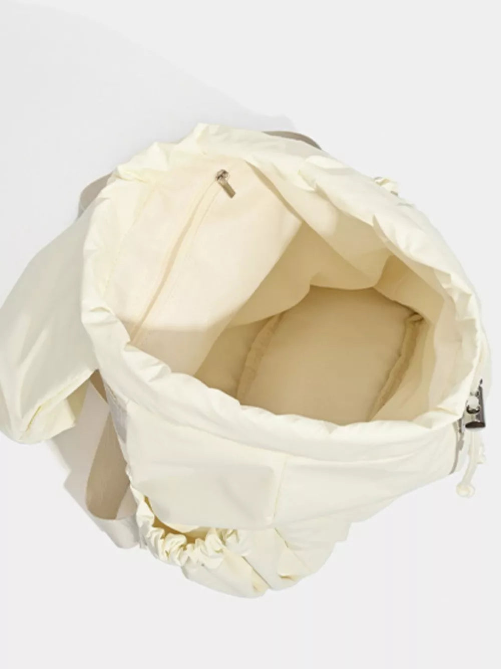 Cream nylon drawstring backpack interior with zip pocket and padded base.