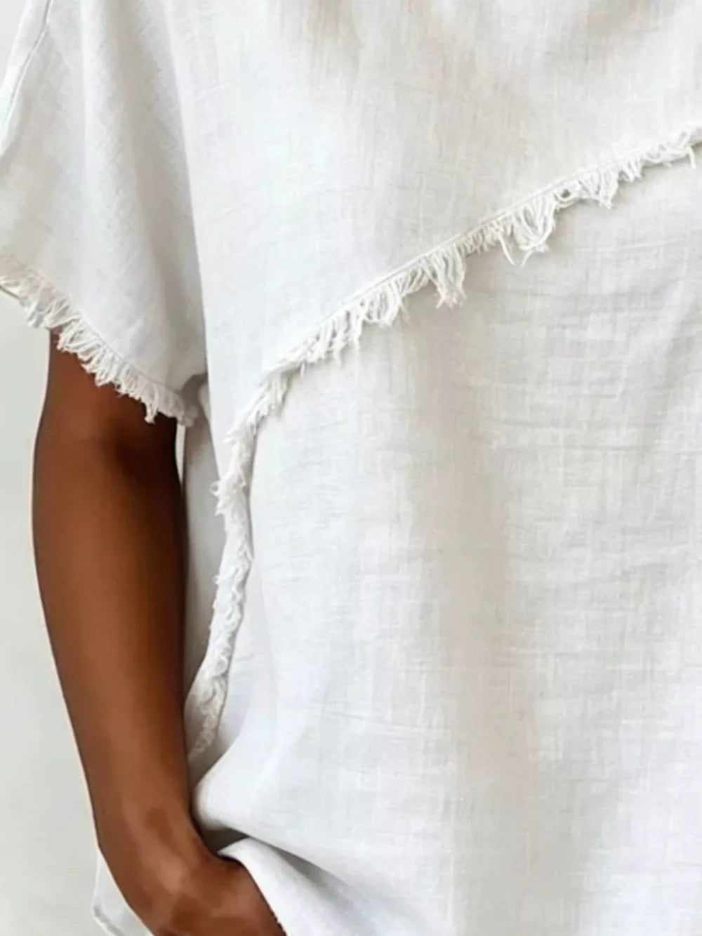 White relaxed-fit shirt with frayed asymmetrical hem and short sleeves.