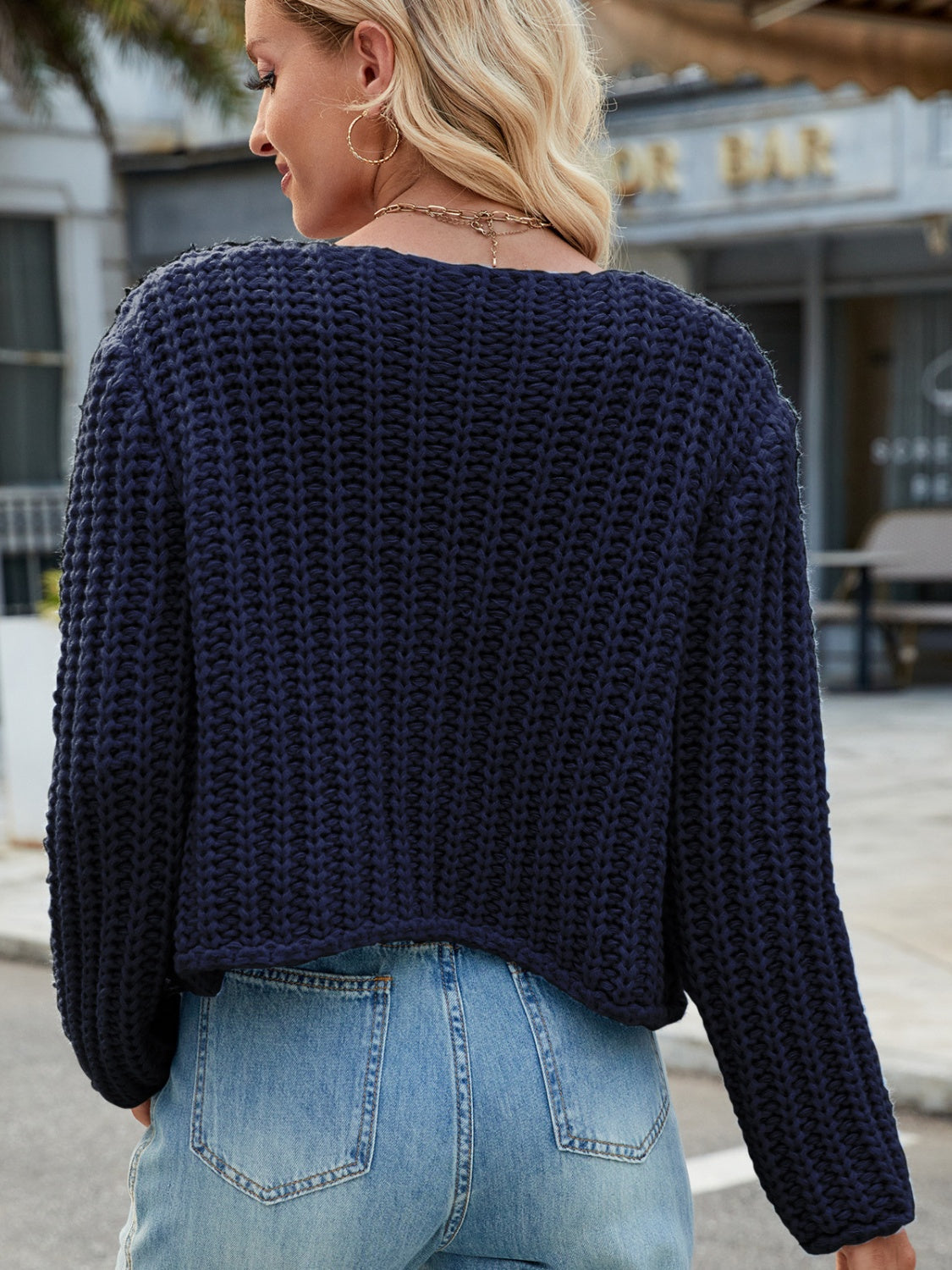 Dark blue chunky knit acrylic cardigan with gold buttons and pockets.