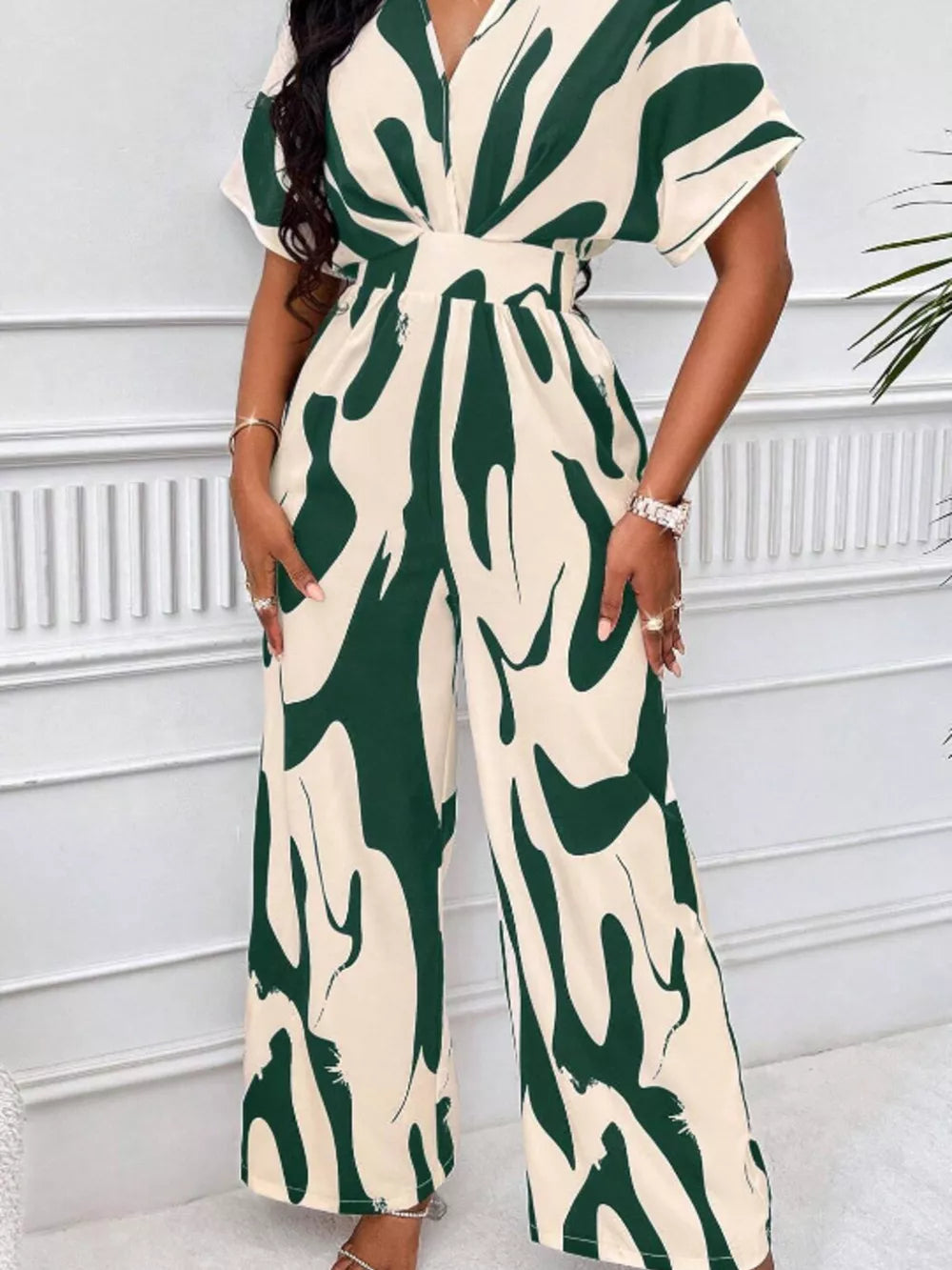 Chic abstract print wide-leg romper in green and cream with short sleeves and a V-neck.