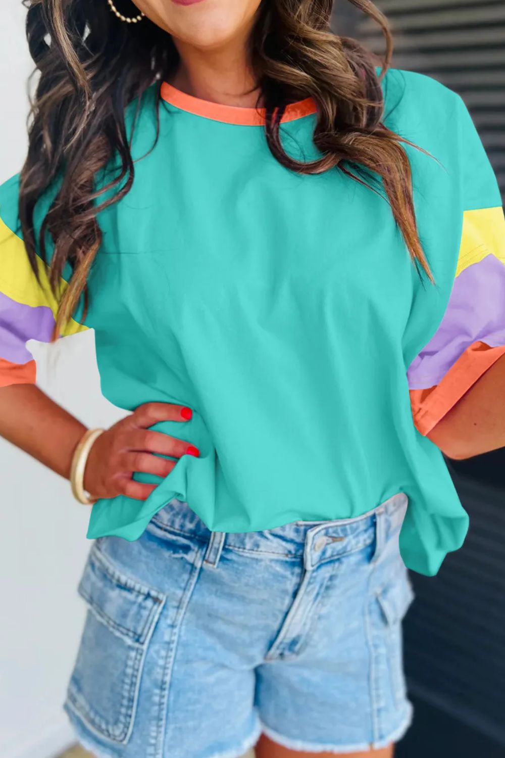 Teal raglan tee with colorblock sleeves in yellow, purple, and orange, and an orange neckline.