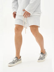 Gray fleece lounge shorts with raw edge hem and drawstring, paired with patterned sneakers.
