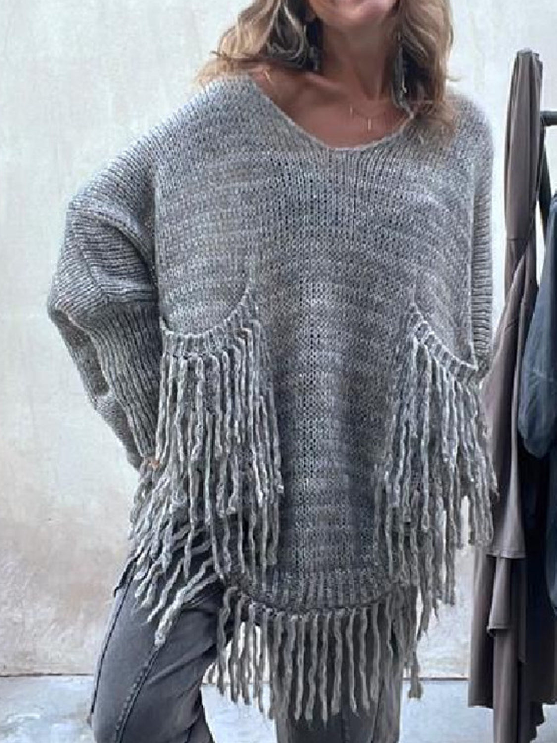 Dark gray knit poncho sweater with fringe detail on pockets and hem.