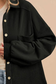 Black waffle knit shacket with gathered sleeves, button front, and chest pocket.