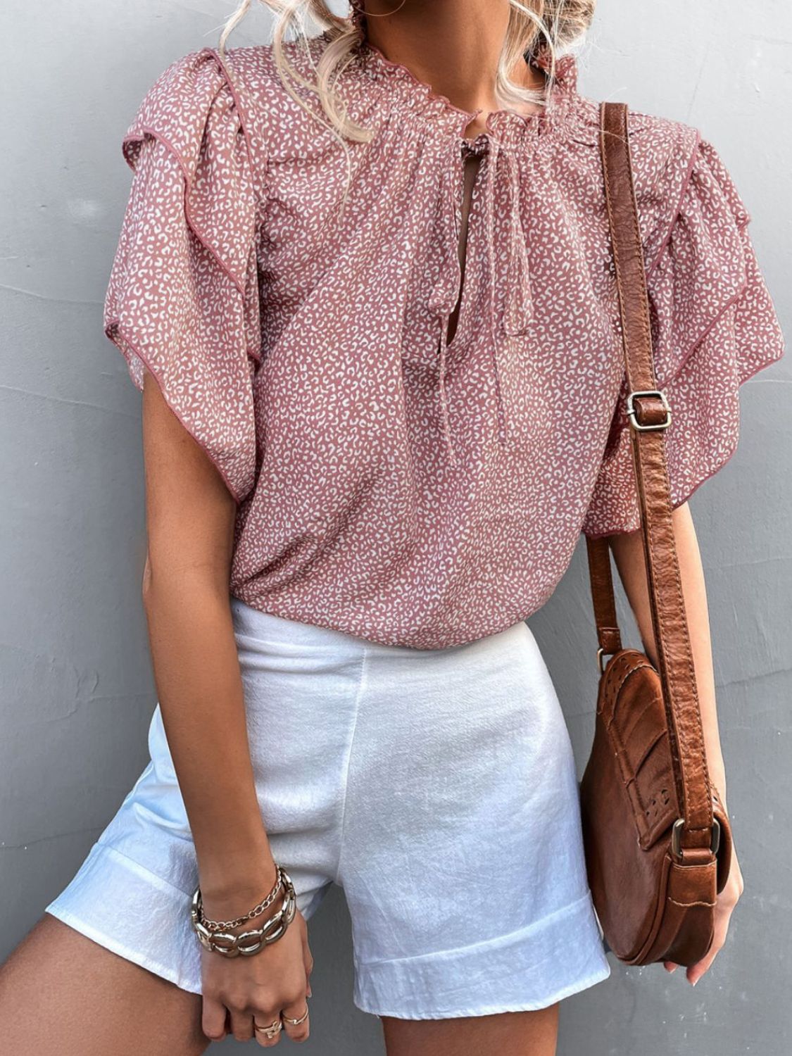 Pink ditsy print blouse with ruffle sleeves and tie neck, styled with white shorts.