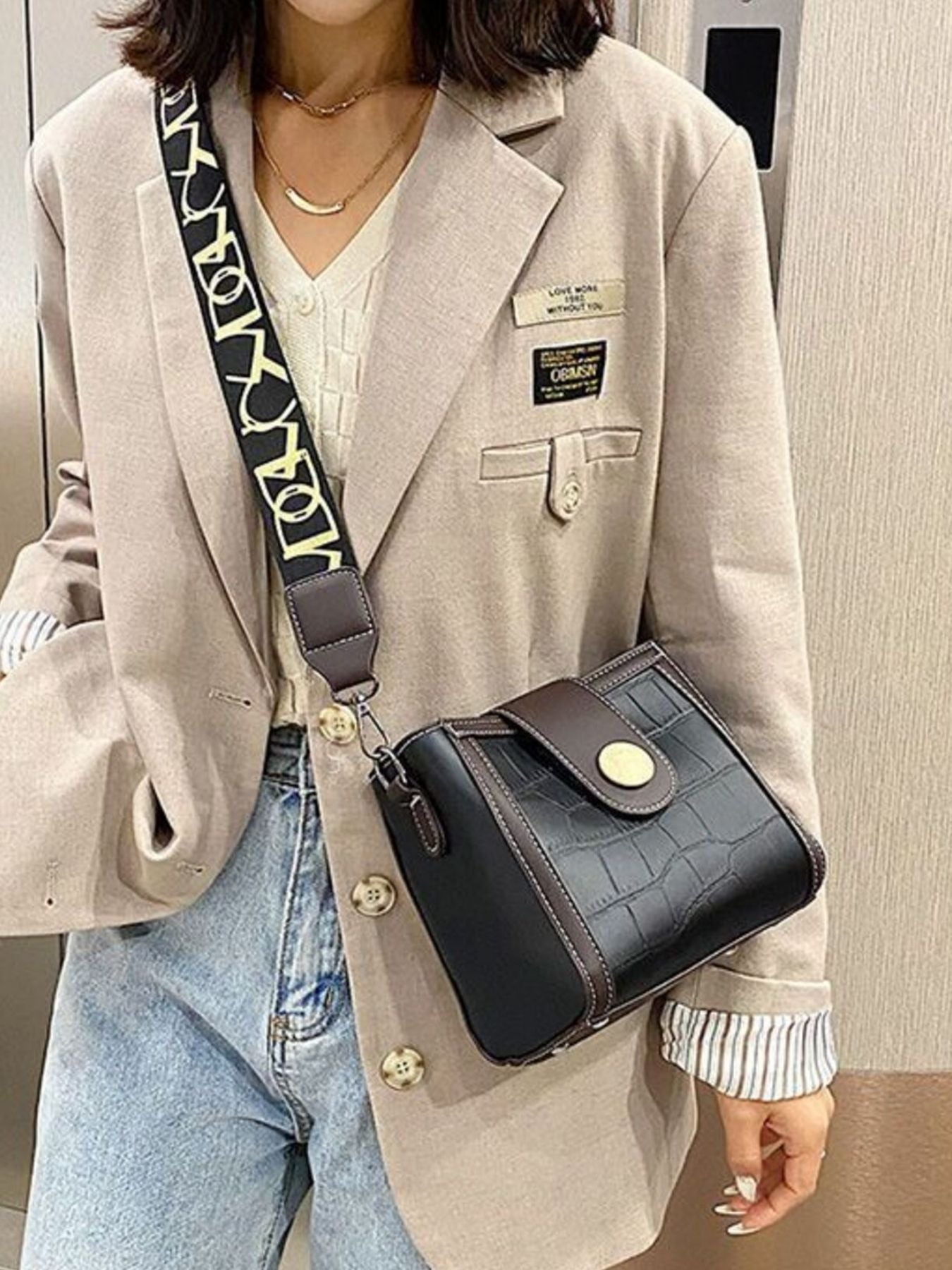 Black crocodile pattern mini crossbody bag with decorative strap and gold button closure.