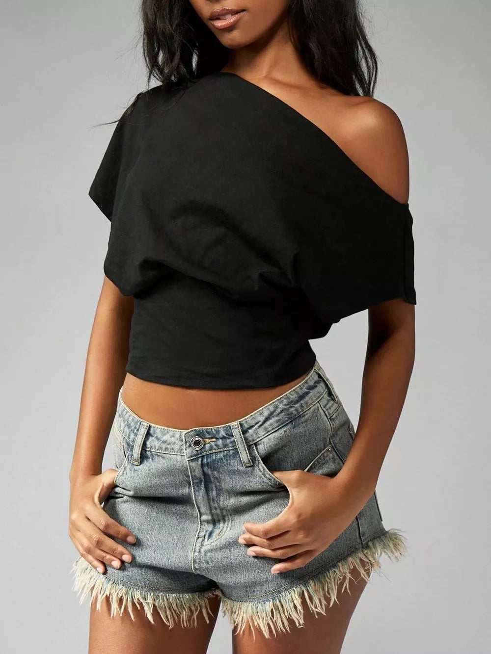 Black asymmetrical crop t-shirt with draped fit and off-the-shoulder neckline.