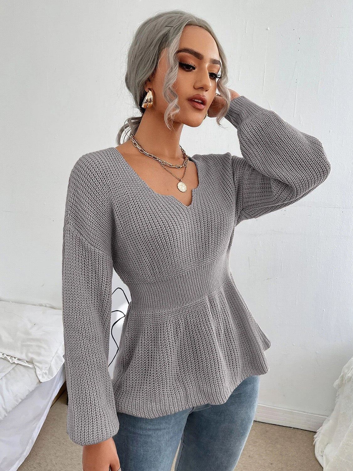 Grey peplum knit sweater with scallop neckline and long sleeves.