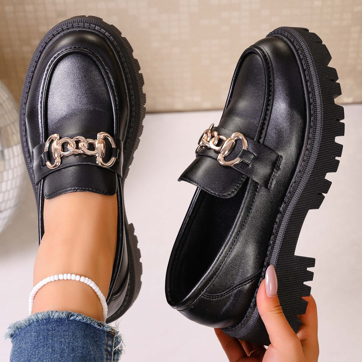 Chunky lug sole loafers in gloss black with gold chain detail.