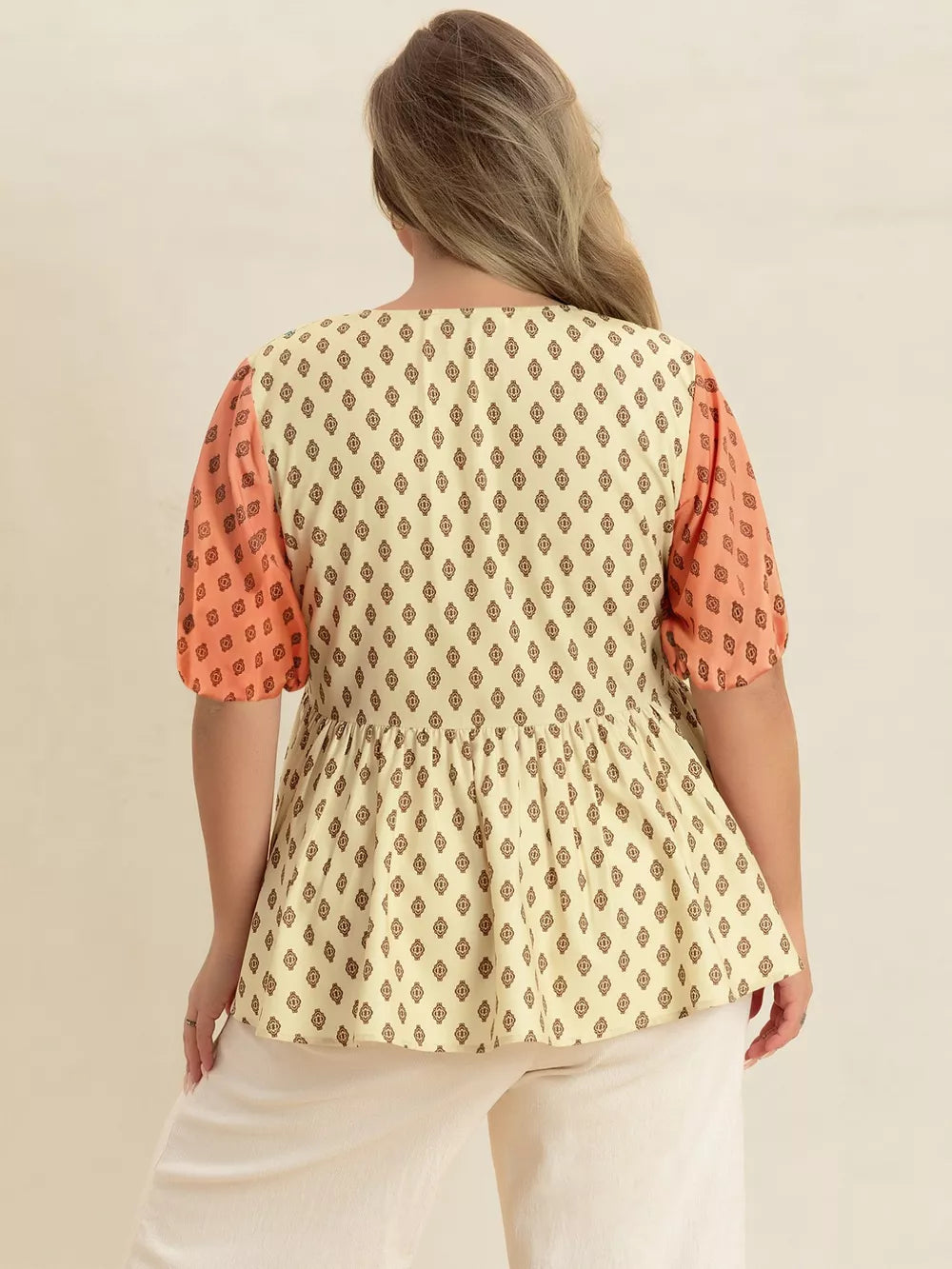 Vibrant geometric peplum shirt with coral sleeves and a cream diamond print.