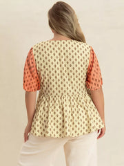 Vibrant geometric peplum shirt with coral sleeves and a cream diamond print.