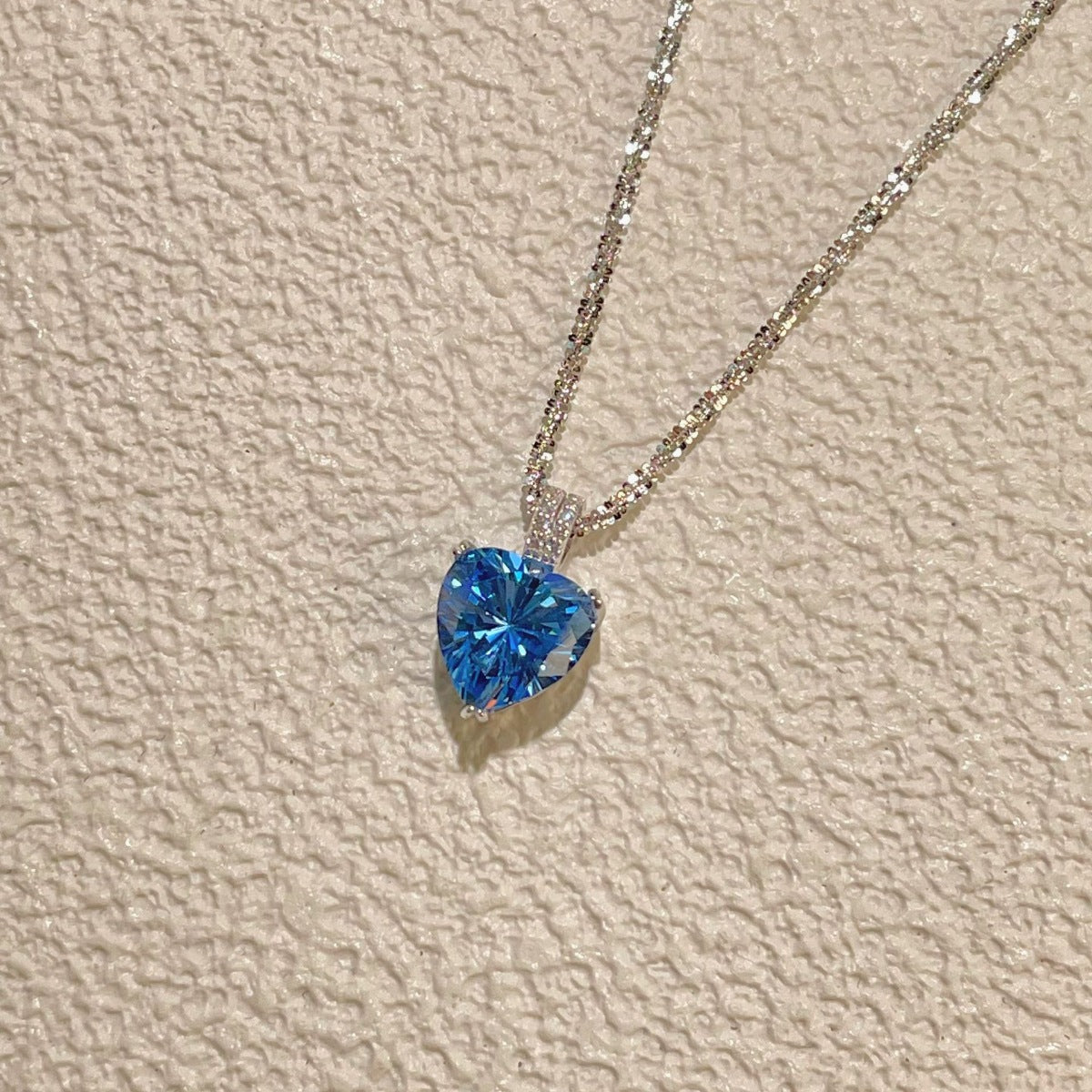 Dazzling heart pendant necklace in silver with a blue gemstone and delicate chain.