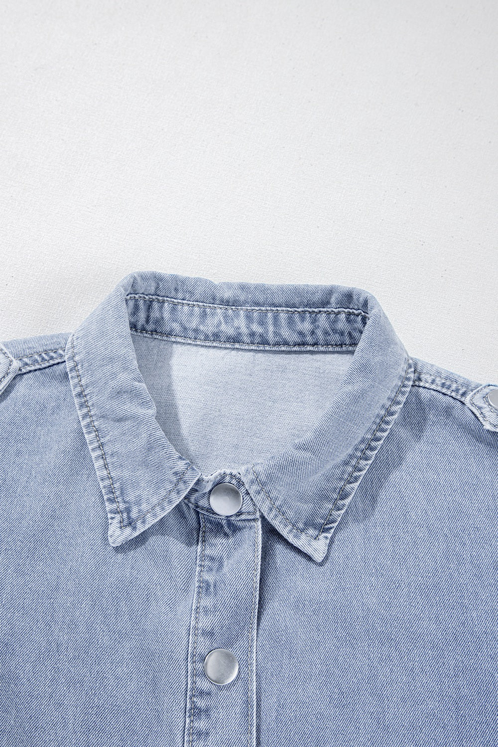 Light blue denim shirt jacket with button front and collar detail.