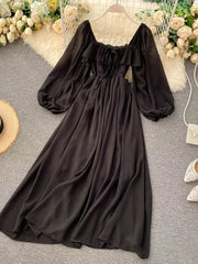 Black A-line maternity dress with square neck, ruffled detail, tie front, and balloon sleeves.