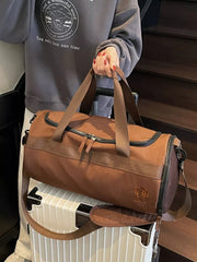 Brown Oxford cloth duffel bag with carry handles and adjustable strap.