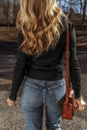 Black long sleeve crewneck top with subtle texture, styled with jeans and a brown crossbody bag.