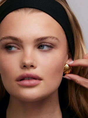 Gilded scallop ear studs in gold, featuring a textured, layered design.