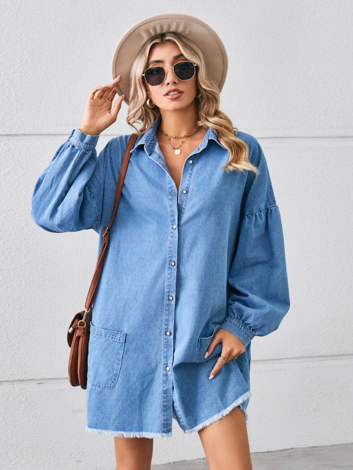 Denim shirtdress in sky blue with voluminous sleeves, button front, chest pockets, and frayed hem.